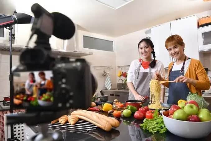 A woman and a man are shooting a video while cooking in the kitchen for YouTube.